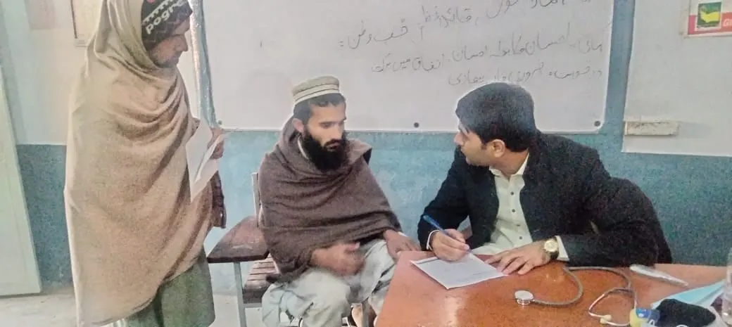 A doctor consults with a patient at a desk during the camp